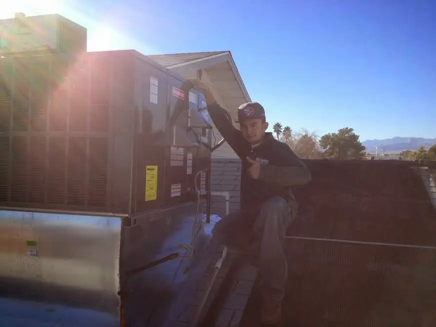 HVAC technician performing AC Tune-Up on a rooftop unit in Ghent